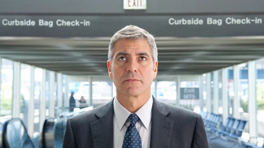 A man standing in the airport and staring at the board