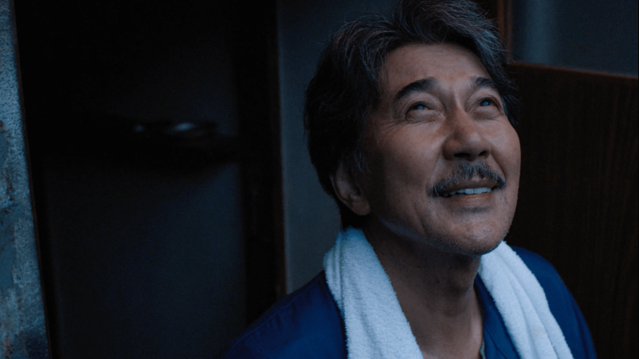 A close-up portrait of a man with an energetic, happy expression, his eyes wide open and lips slightly parted in a smile, wearing a white towel or robe, exuding a fresh and positive mood for the start of the day.